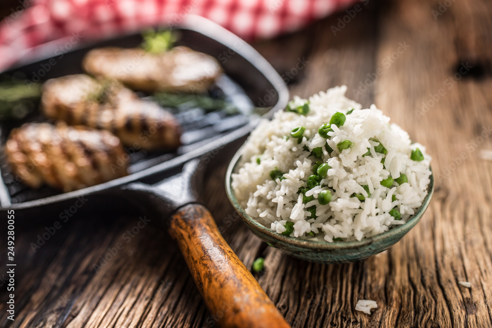 Rice basmati with green peas in bowl and grilled chicken breast in the background Rice basmati with green peas in bowl and grilled chicken breast in the background