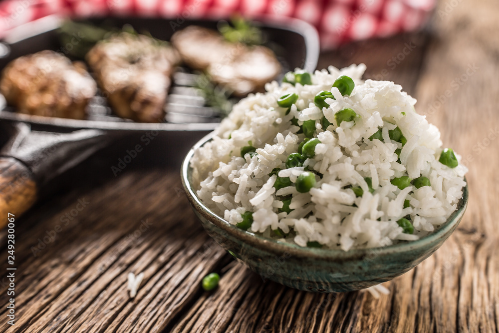 Rice basmati with green peas in bowl and grilled chicken breast in the background Rice basmati with green peas in bowl and grilled chicken breast in the background