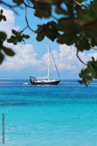 A sailboat parked at the beach  turquoise waters and beautiful white sand. 
