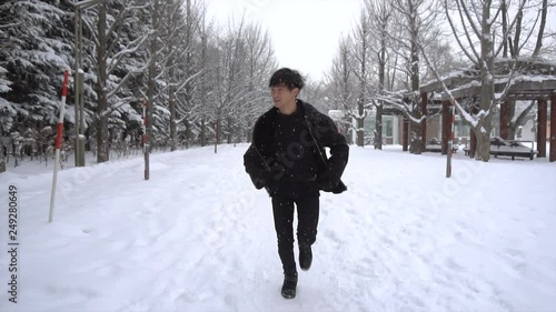 Young Asian Man Running on Snow Covered Path in Park Slow Motion photo