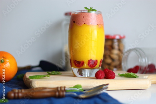 Fresh Orange and mango smoothie drink with raspberry ice cream on wooden board.