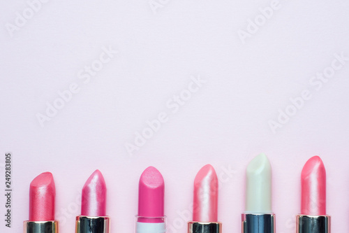 Set of colored pink lipsticks on pink background. Women's cosmetics. Selective focus. Copy space.
