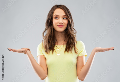 choice and people concept - smiling young woman or teenage girl in blank yellow t-shirt holding something imaginary over grey background photo
