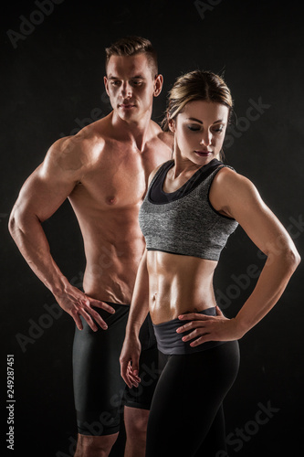Sporty young couple posing on black background