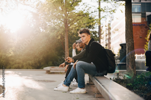 Thoughtful young man sitting with friends in skate park