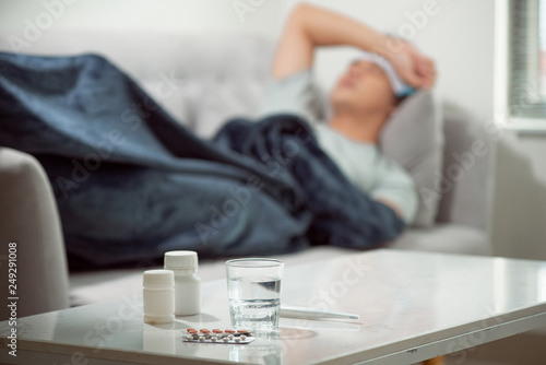 Photo sick wasted man lying in sofa suffering cold and winter flu virus having medicin
