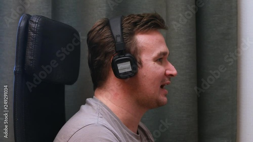 A young man sitting in a chair listening to music in headphones incredibly feeling the rhythm of music. Musical inspiration at work