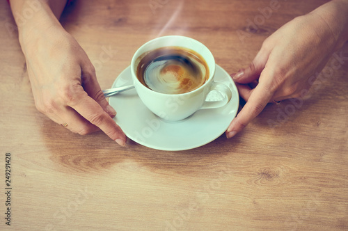 Closeup hand with a cup of cappuccino coffee. Color toning in retro style. Lifestyle person at the weekend.