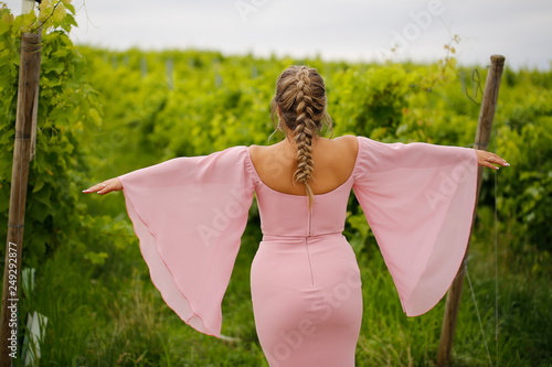 Beautiful woman posing in red dress in front of vineyard