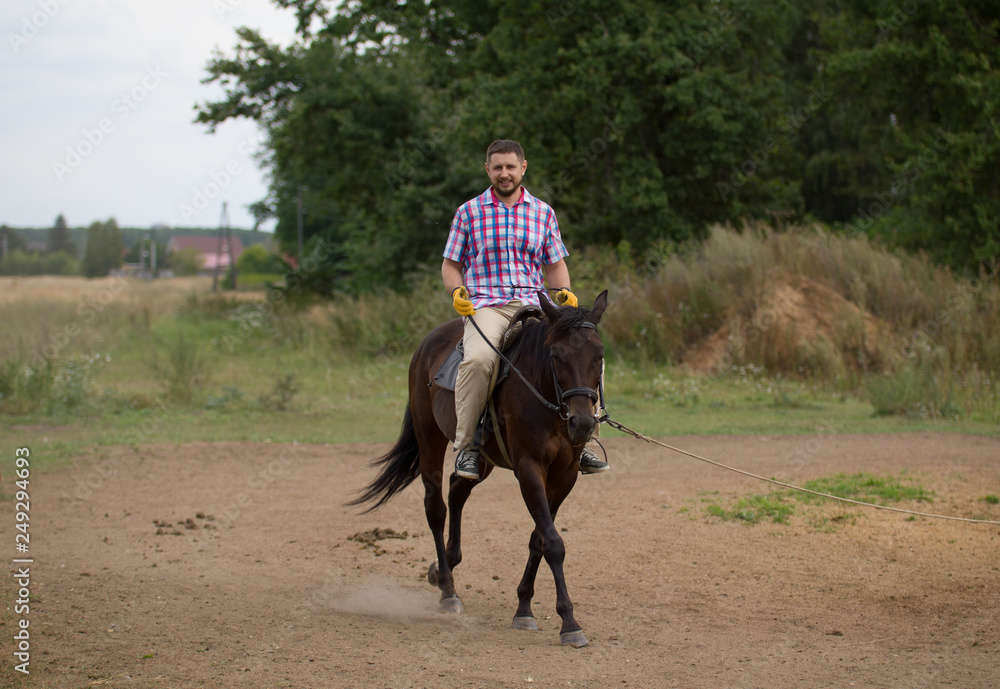 A man in checkered shirt riding a horse on the field. A man in checkered shirt riding a horse on the field.