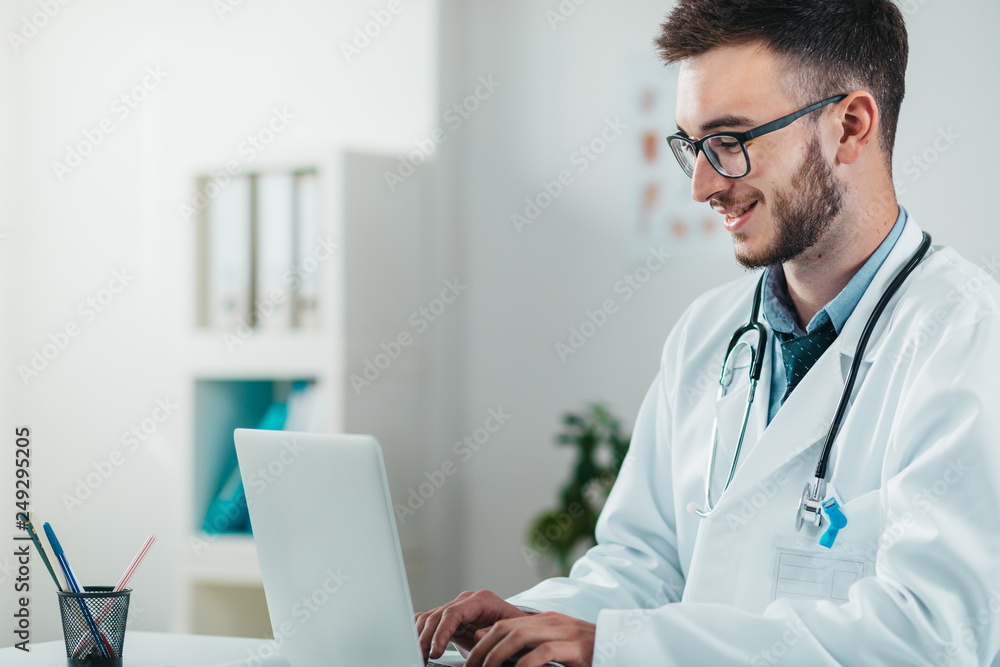 Portrait of Young Doctor on the Job working on laptop Portrait of Young Doctor on the Job working on laptop
