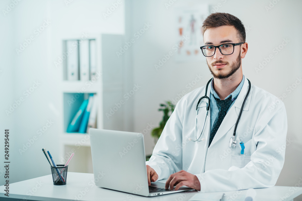 Portrait of Young Doctor on the Job working on laptop Portrait of Young Doctor on the Job working on laptop