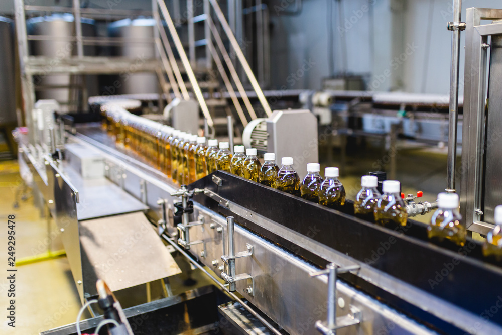 Bottling factory - Apple juice bottling line for processing and bottling juice into bottles. Selective focus. Bottling factory - Apple juice bottling line for processing and bottling juice into bottles. Selective focus.