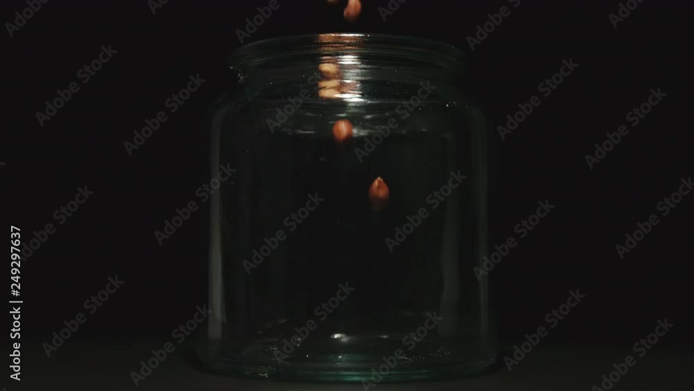 SLOW MOTION: Peeled peanuts falling into a glass jar SLOW MOTION: Peeled peanuts falling into a glass jar
