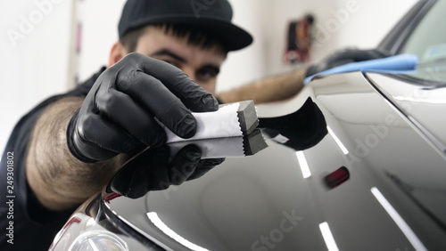 Professional ceramics handler apply different layers to the car using an applicator (sponge, fiber) immediately checking the effect. Concept from: Autodetailing, Special Ceramics, Nano technology. photo