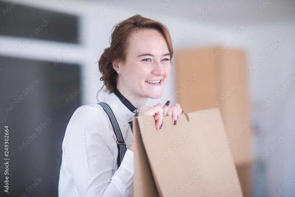 Junge Frau mit weißer Bluse, Hosenträger, bow tie und Papiertüte zu Hause Junge Frau mit weißer Bluse, Hosenträger, bow tie und Papiertüte zu Hause
