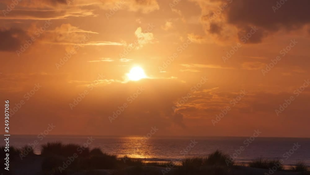 Time lapse of a sunset at the beach in Netherlands in warm colours and some clouds Time lapse of a sunset at the beach in Netherlands in warm colours and some clouds