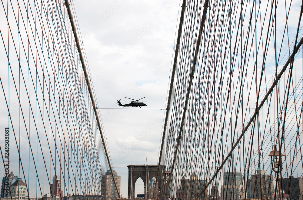 Fototapeta premium Undefined helicopter flying over Brooklyn Bridge in New York City. USA