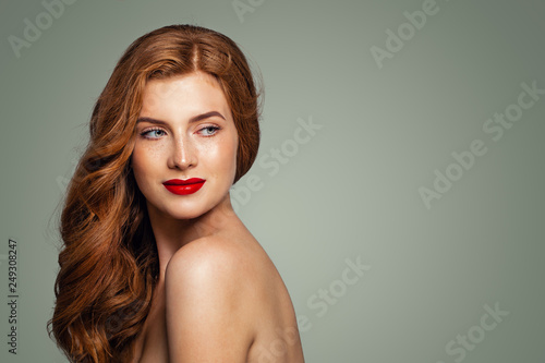 Redhead woman smiling. Red head girl with curly hairstyle looking over shoulder. Natural authentic beauty