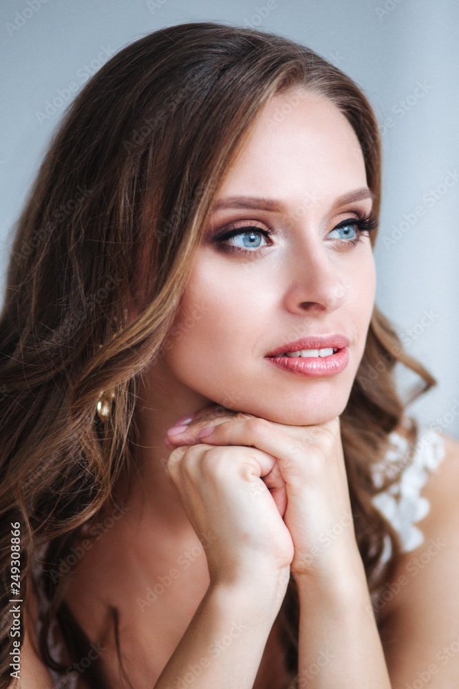 Naklejka premium Gorgeous bride portrait indoor. Beautiful bride with wedding makeup and jewelry on long curly hair.