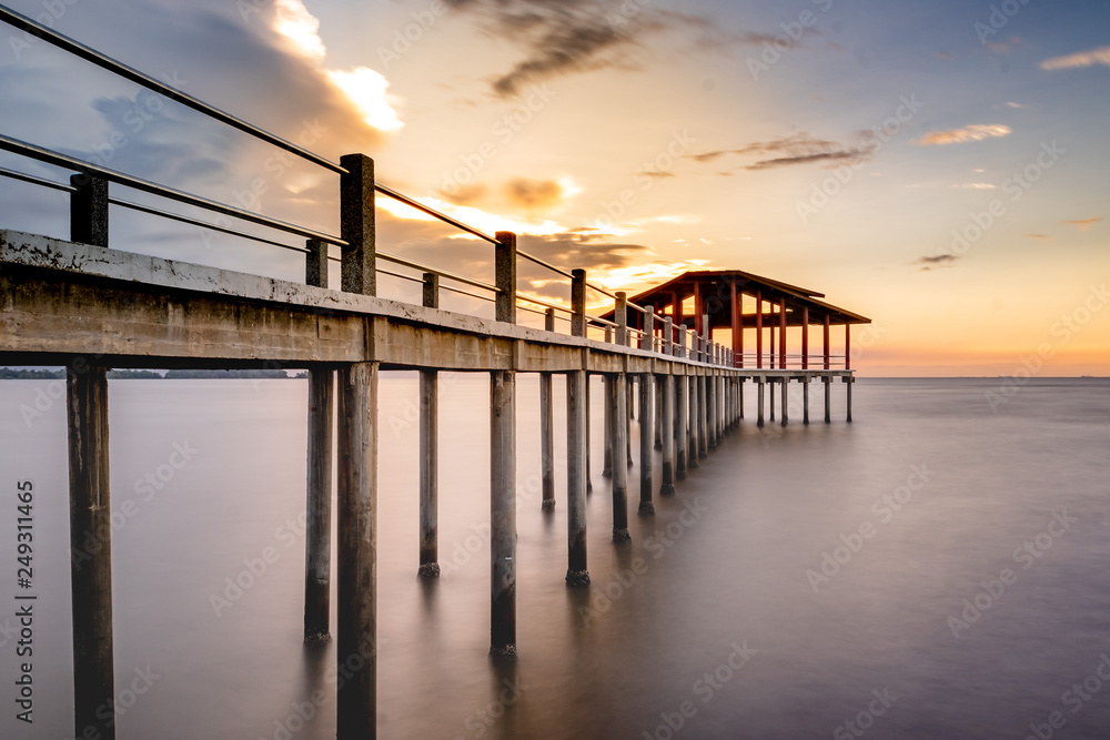 Naklejka premium Long exposure of a jetty leading to coast during sunset.