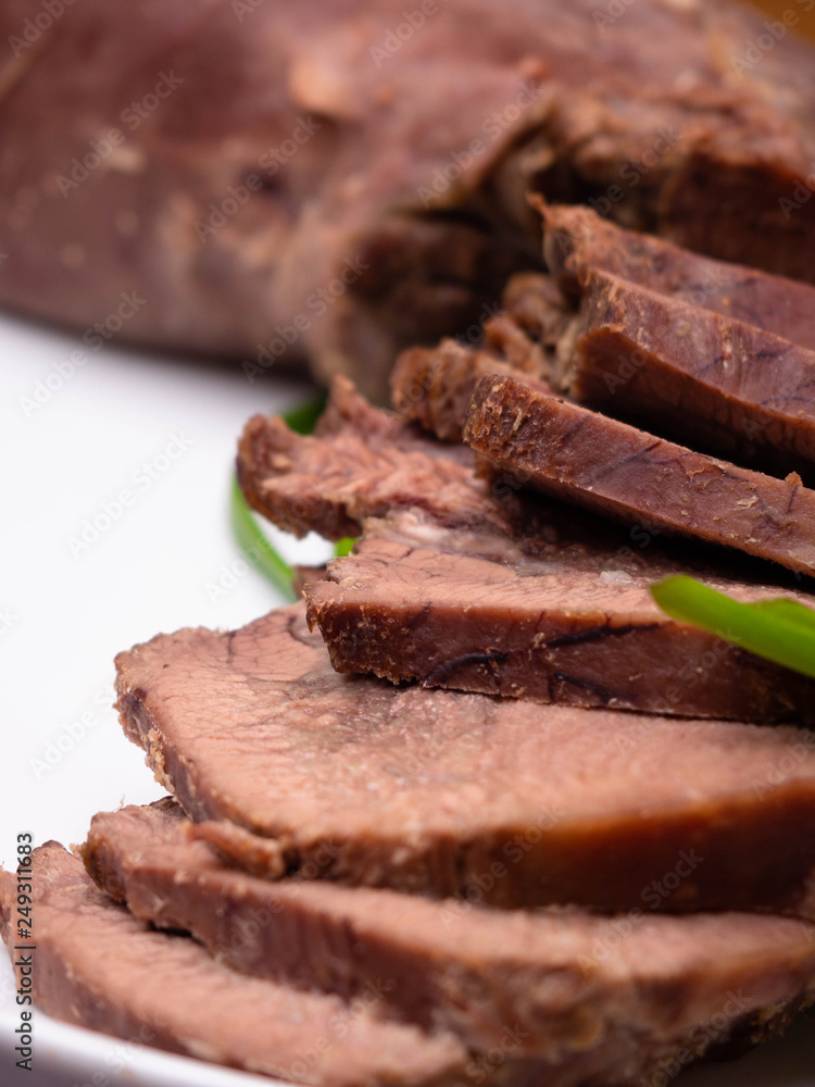 Boiled beef tongue with green onion is served on a plate in a restaurant, selective focus Boiled beef tongue with green onion is served on a plate in a restaurant, selective focus