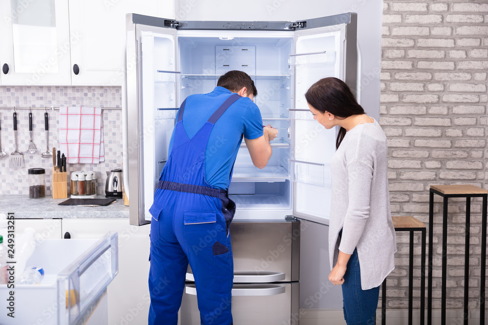 Repairman Fixing Refrigerator With Screwdriver Repairman Fixing Refrigerator With Screwdriver