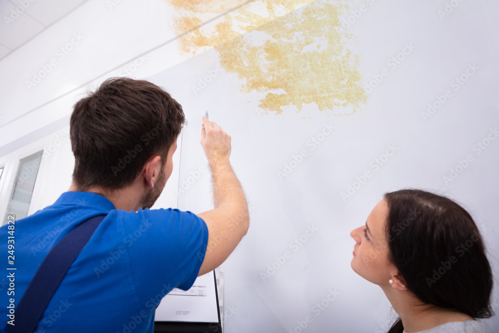 Worker Writing On Clipboard With Woman Standing Worker Writing On Clipboard With Woman Standing