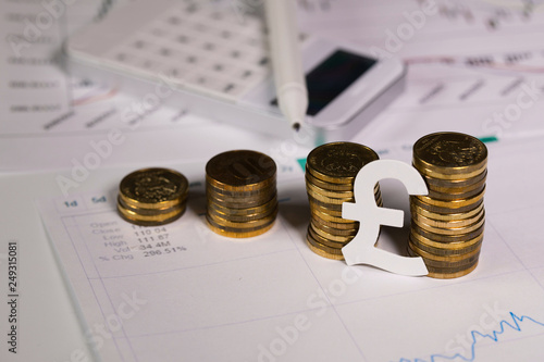 Paper sign of British pound at stacks of coins. photo