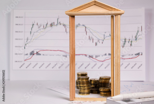 Coins on a stock market charts behind opened small wooden door. photo