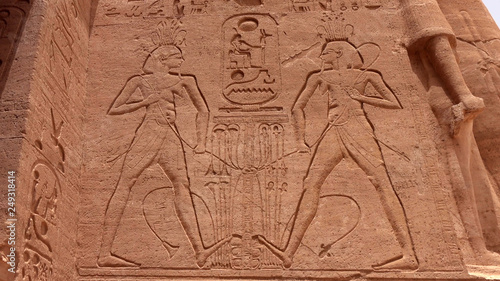 Ancient Egyptian carvings of people and hieroglyphics on the exterior walls of an ancient temple
