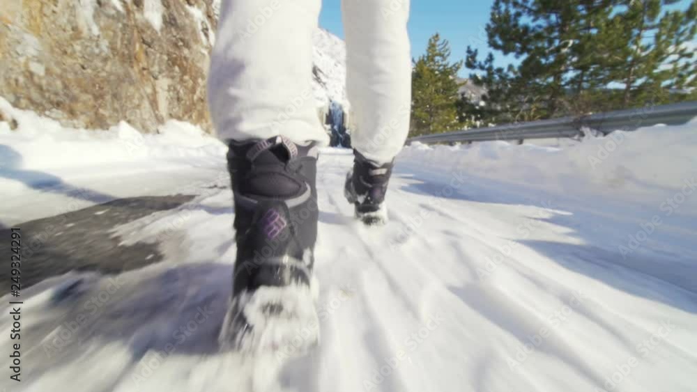 camera moving behind a hiker on road with snow in winter. low angle view camera moving behind a hiker on road with snow in winter. low angle view