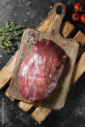 Obraz na płótnie Raw reindeer meat on wooden Board on dark background w salonie