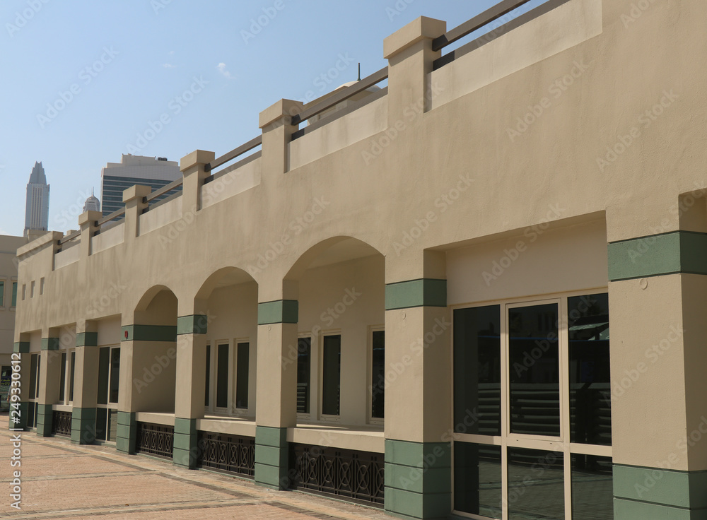 one floor white building with skyscrapers behind one floor white building with skyscrapers behind