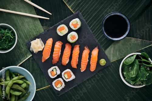 Sushi Nigiri Lachs und Maki Rolls Essen auf scharzer SChiefertafel und Bananenblätter