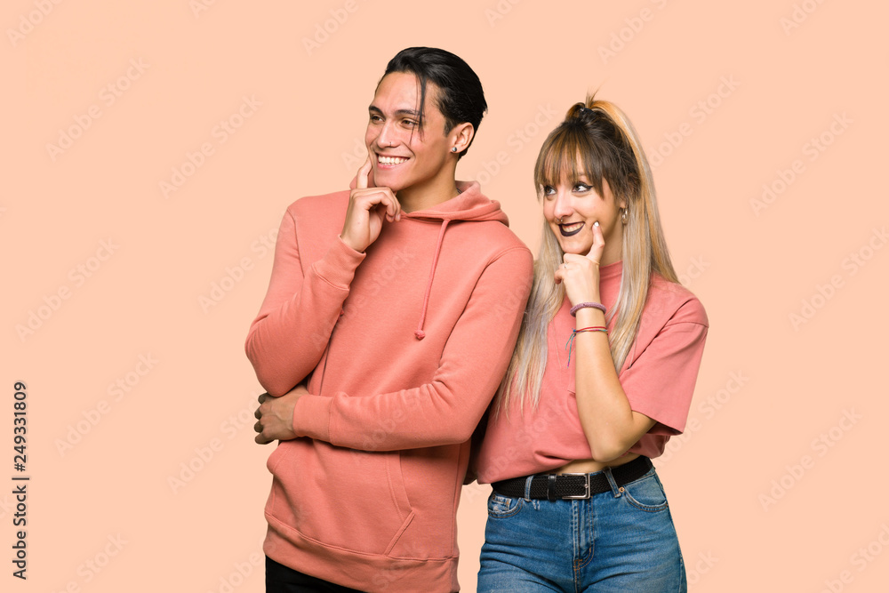Young couple thinking an idea while looking up over pink background Young couple thinking an idea while looking up over pink background