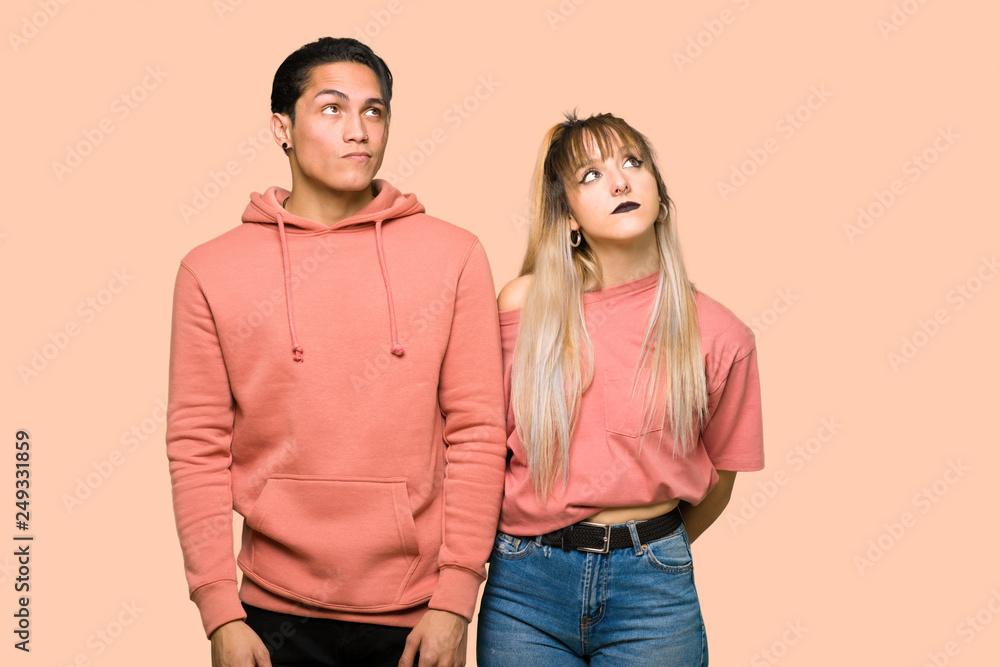 Young couple looking up with serious face over pink background Young couple looking up with serious face over pink background