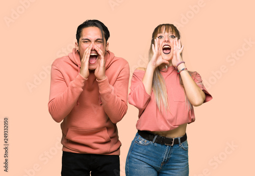 Young couple shouting and announcing something over pink background