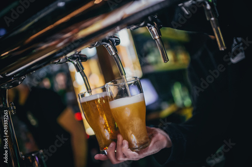 The man behind the bar pours beer holding a mug in his hand