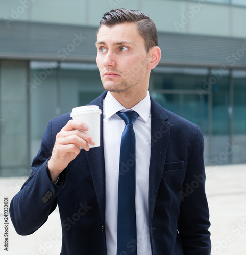 Businessman is drinking coffee outdoors