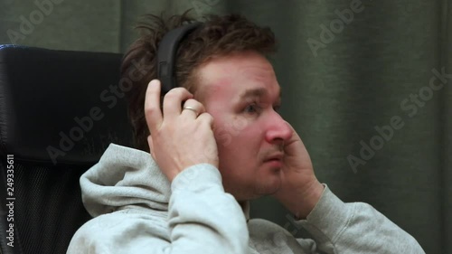 a man sits in a chair and emotionally listens to music with headphones