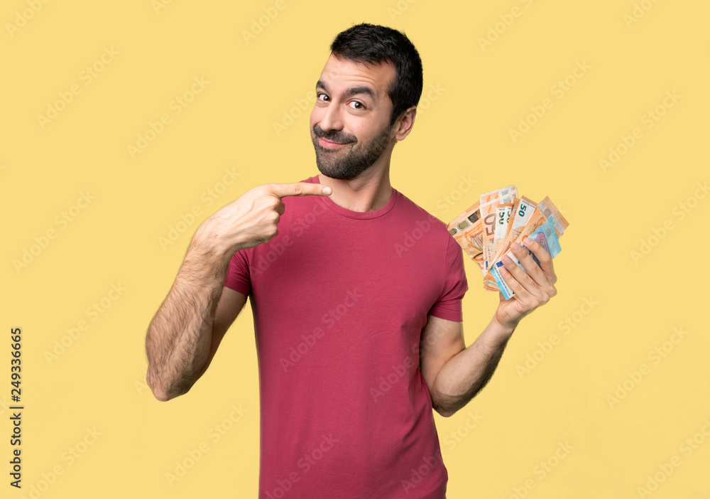 Man taking a lot of money holding copyspace imaginary on the palm to insert an ad on isolated yellow background Man taking a lot of money holding copyspace imaginary on the palm to insert an ad on isolated yellow background