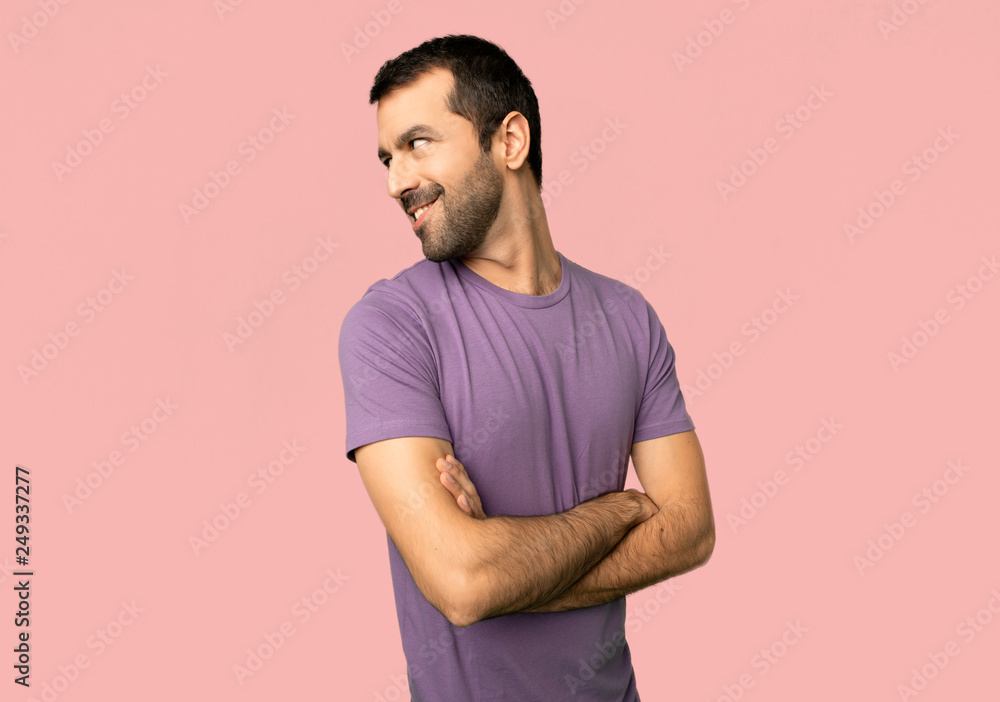 Handsome man looking over the shoulder with a smile on isolated pink background Handsome man looking over the shoulder with a smile on isolated pink background
