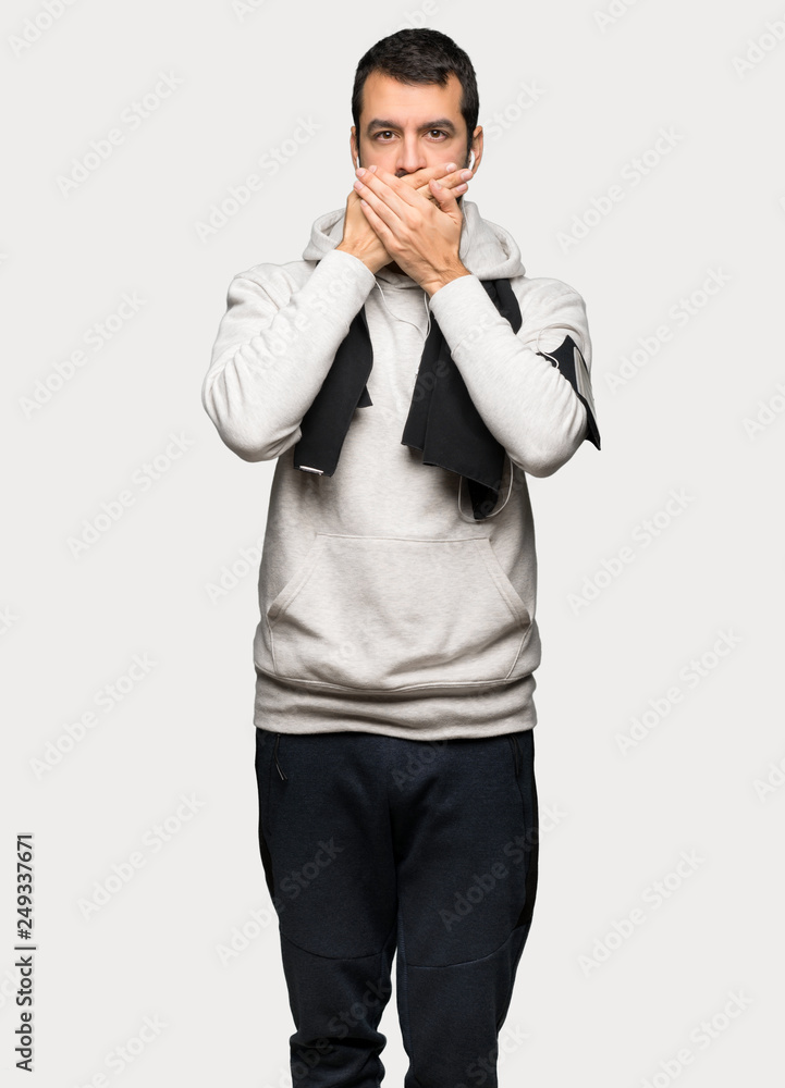Sport man covering mouth with hands for saying something inappropriate over isolated grey background Sport man covering mouth with hands for saying something inappropriate over isolated grey background