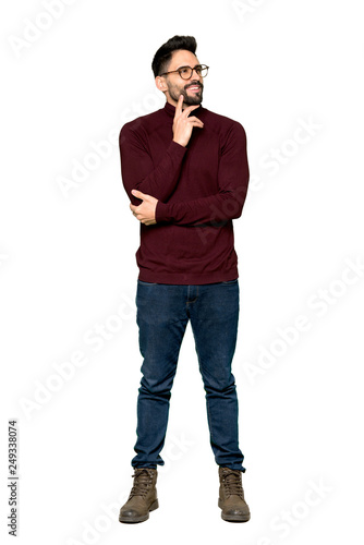 Full-length shot of Handsome man with glasses thinking an idea while looking up on isolated white background © luismolinero