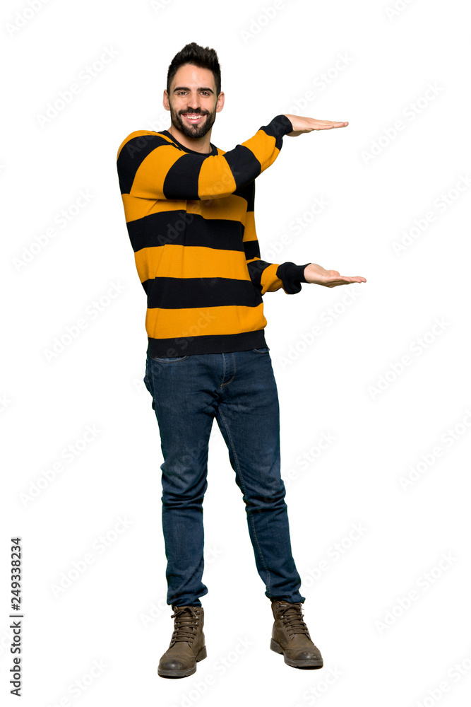 Full-length shot of Handsome man with striped sweater holding copyspace to insert an ad on isolated white background Full-length shot of Handsome man with striped sweater holding copyspace to insert an ad on isolated white background
