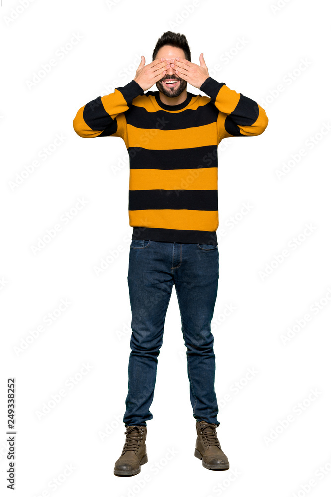 Full-length shot of Handsome man with striped sweater covering eyes by hands. Surprised to see what is ahead on isolated white background Full-length shot of Handsome man with striped sweater covering eyes by hands. Surprised to see what is ahead on isolated white background