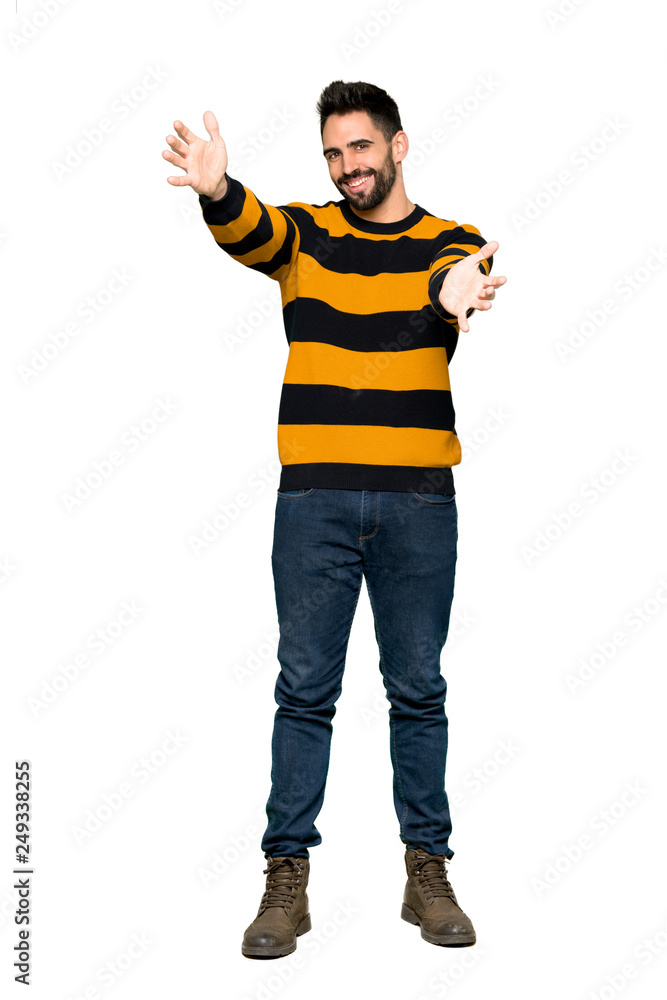 Full-length shot of Handsome man with striped sweater presenting and inviting to come with hand on isolated white background Full-length shot of Handsome man with striped sweater presenting and inviting to come with hand on isolated white background
