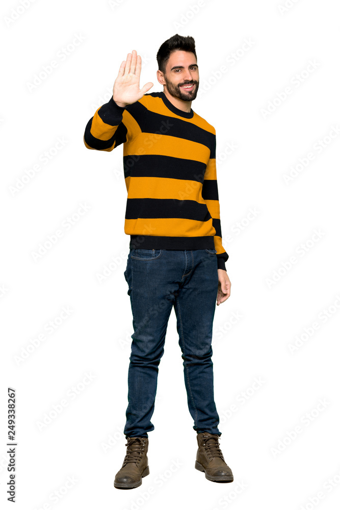 Full-length shot of Handsome man with striped sweater saluting with hand with happy expression on isolated white background Full-length shot of Handsome man with striped sweater saluting with hand with happy expression on isolated white background