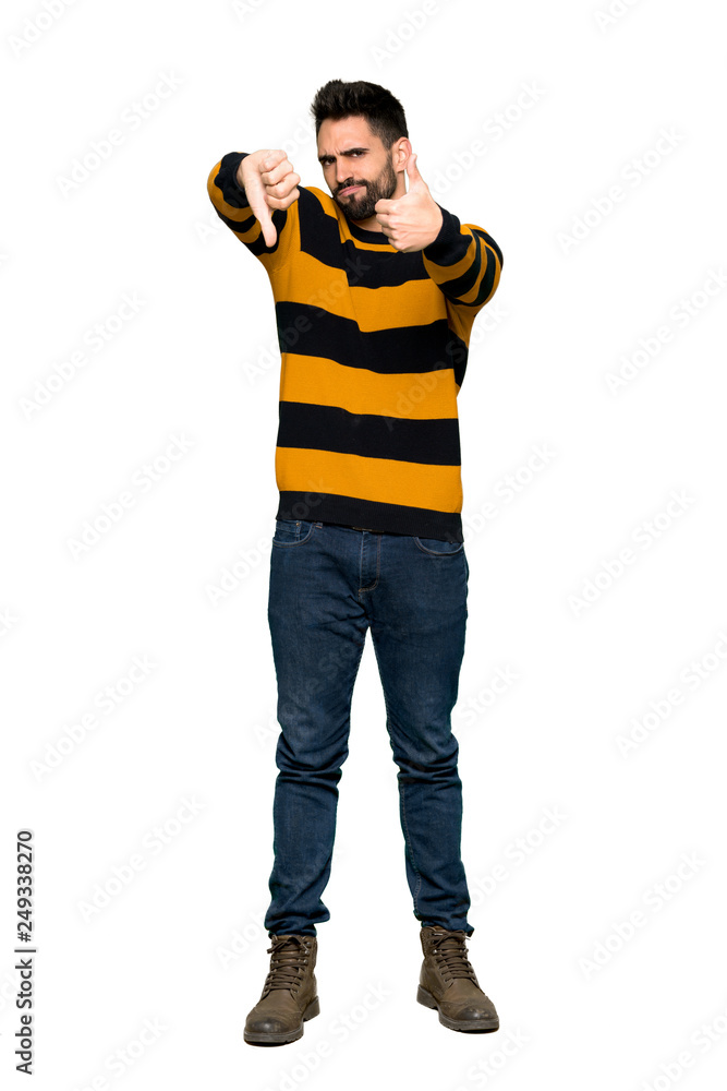 Full-length shot of Handsome man with striped sweater making good-bad sign. Undecided between yes or not on isolated white background Full-length shot of Handsome man with striped sweater making good-bad sign. Undecided between yes or not on isolated white background